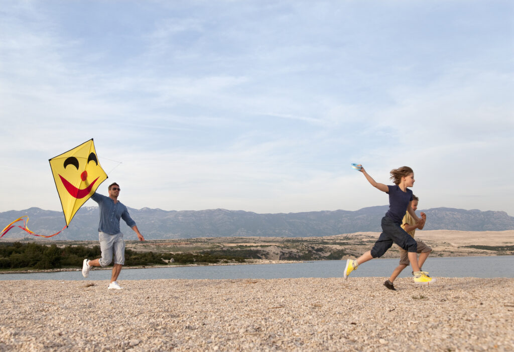 Father and children with kite at beach