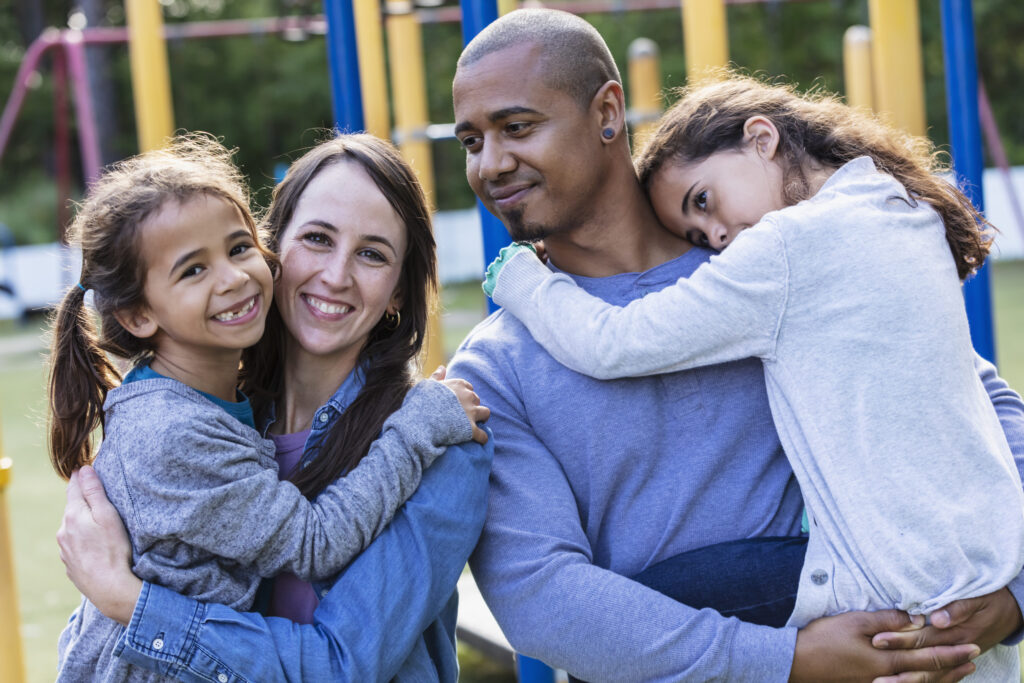 Mixed race family with two girls have fun on playground