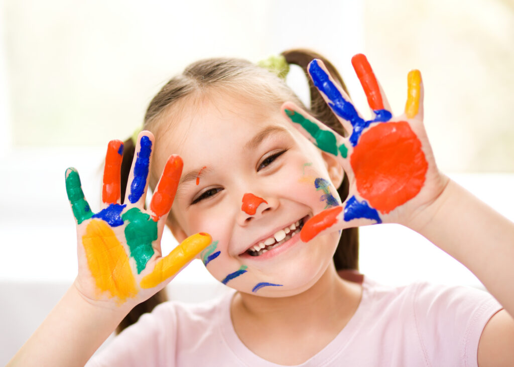 Portrait of a cute girl playing with paints